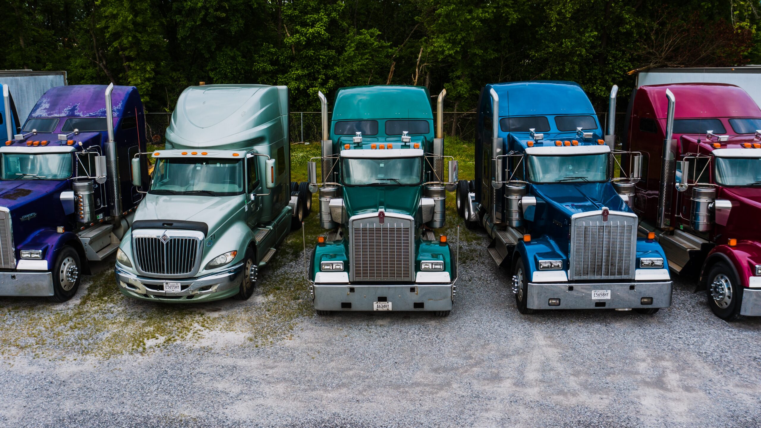 An bird's-eye view of a row of 5 primary-colored semi-trailer semi-trucks