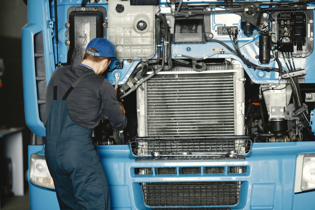 A mechanic working on the inside of a semi-truck hood