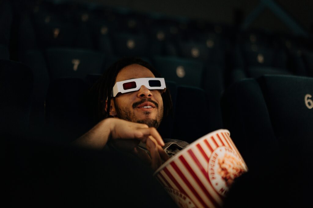 A man enjoying a movie smiling with popcorn in hand