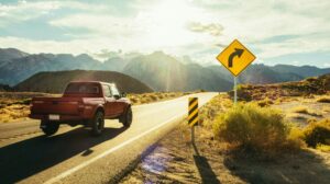 A pickup truck rounding a corner on a sunny patch of highway