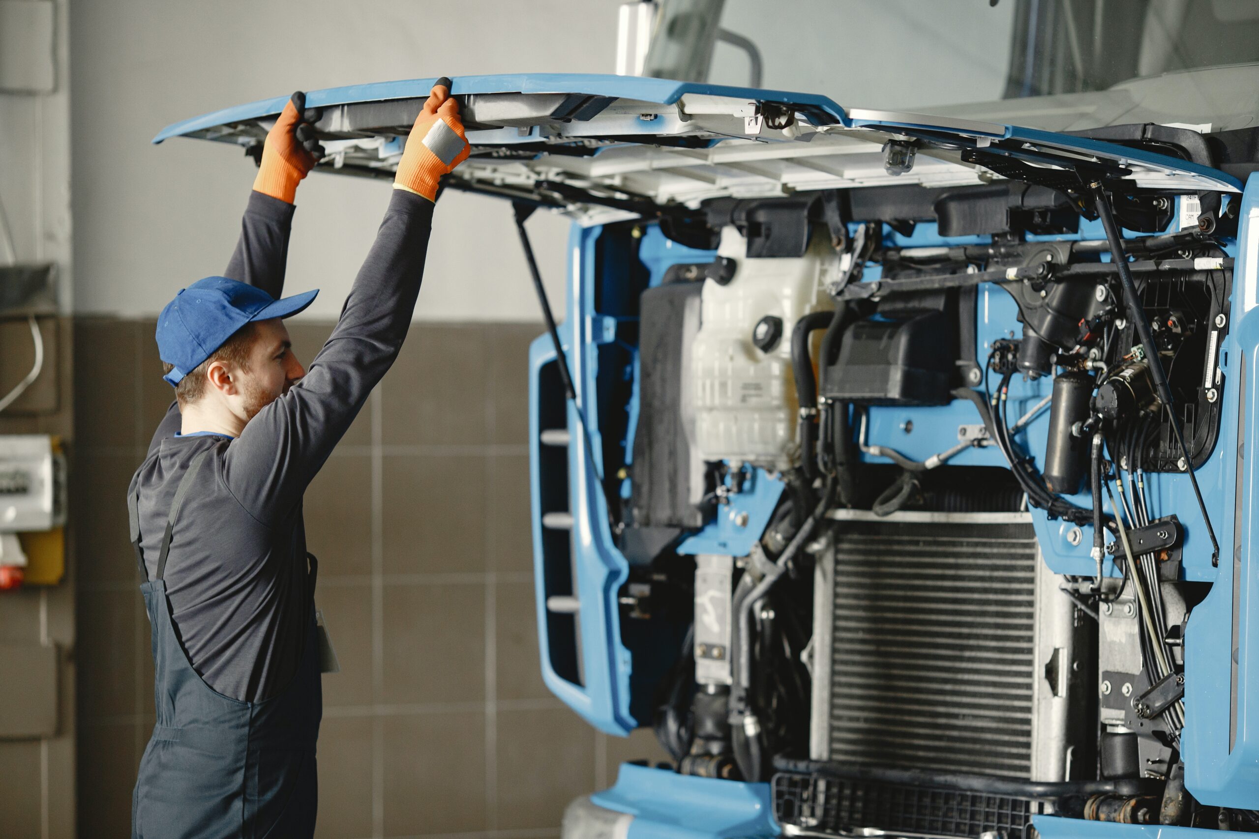 A person opening the hood of a semi truck